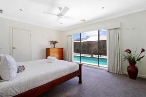 a bedroom with a bed and a view of a pool at The Grand Holiday House in Yarrawonga