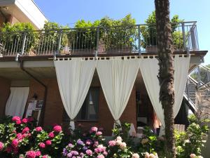 uma varanda com cortinas brancas e flores cor-de-rosa em sebante em Cervia