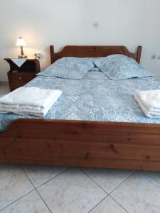 Schlafzimmer mit einem Holzbett mit blauer Decke in der Unterkunft NEW PANORAMA STUDIOS in Paralio Astros