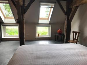 a bedroom with four windows and a white bed at Op 't Oorbeck in Enschede