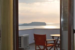 a view of the ocean from a balcony with a table and chair at Athevillas Antonis in Mína
