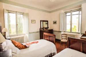 a bedroom with a bed and a dresser and two windows at Tenuta di Spannocchia in Rosia