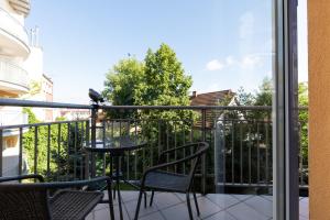 a balcony with two chairs and a bird on a railing at Jantar Home - Portowa in Kołobrzeg