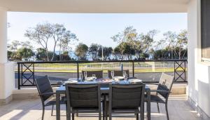 a dining room with a table and chairs on a balcony at Bay Royal Apartments in Byron Bay