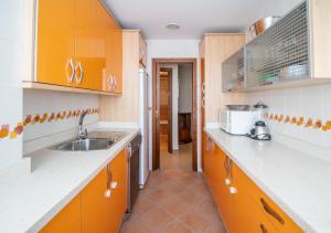 una cucina con armadi arancioni e lavandino di Apartamento Paseo Maritimo 27 a Cadice