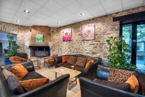 a living room with leather furniture and a brick wall at LE SOUFFLE VERT in Cussac