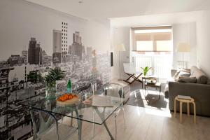 sala de estar con mesa de cristal y mural de la ciudad en Eric Vökel Boutique Apartments - Atocha Suites, en Madrid