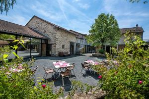 a patio with tables and chairs in front of a building at LE SOUFFLE VERT in Cussac