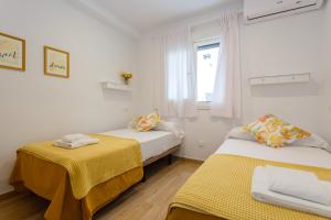 two beds in a room with a window and a yellow blanket at Casa Ros-PLAYA free parking by Cadiz4Rentals in Cádiz