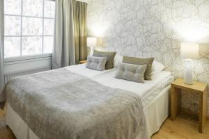 a bedroom with a large white bed with two lamps at Lapland Hotels Bear´s Lodge in Sinettä