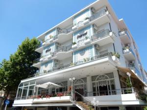 un gran edificio blanco con balcones y plantas en Hotel Saponi en Rímini
