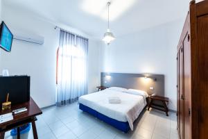 a bedroom with a bed and a desk and a tv at Hotel Meli in Castelsardo