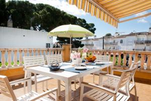 a white table with chairs and an umbrella on a balcony at La marinada in L'Escala