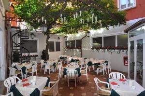 un restaurante con mesas y sillas blancas y un árbol en Hotel Moderno, en Stresa