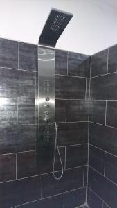 um chuveiro na casa de banho com azulejos pretos em Bungalow Thaï vip jacuzzi interne em Ngaparou