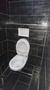 a white toilet in a black tiled bathroom at Bungalow Thaï vip jacuzzi interne in Ngaparou