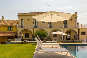 een zwembad met een stoel en een parasol naast een huis bij Dimora Cariga - Home & pool in Giarre +14 foto's