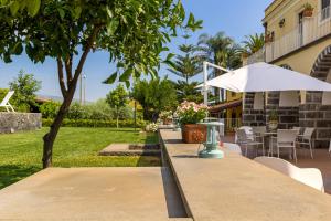 een tafel met een paraplu naast een tuin bij Dimora Cariga - Home & pool in Giarre