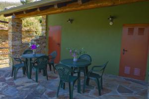 eine Terrasse mit zwei Tischen und Stühlen und einer roten Tür in der Unterkunft RURAL PRADO in San Tirso de Abres