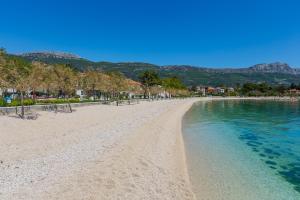a sandy beach with trees and the water at Villa Milena in Trogir