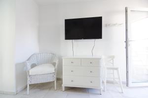 ein Wohnzimmer mit einem TV, einem Stuhl und einer Kommode in der Unterkunft Ribar 1 in Njivice