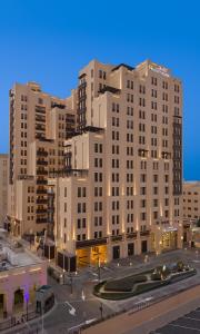 a large white building in a city at night at Hyatt Place Dubai Wasl District Residences in Dubai