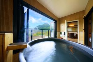 y baño con bañera y ventana grande. en Yufudake Ichibo no Yado Kirara en Yufu
