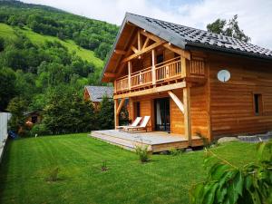 a log cabin with a deck and a chair on a lawn at Chalet de l'Oisans in Allemont