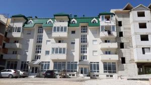 - un grand immeuble avec des voitures garées devant dans l'établissement Apartments Jovana, à Žabljak