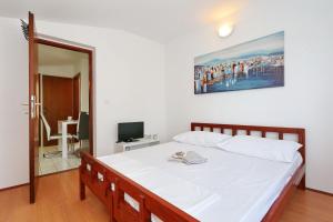 una camera da letto con un grande letto bianco con una foto appesa al muro di Apartments Golub a Nin