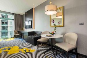 a hotel room with a table and chairs and a desk at Chatrium Hotel Riverside Bangkok in Bangkok