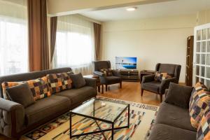 a living room with a couch and chairs and a tv at Vip Apart Hotel in Bursa