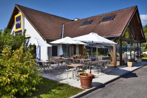 een restaurant met tafels, stoelen en parasols bij Kyriad Genève St-Genis-Pouilly in Saint-Genis-Pouilly