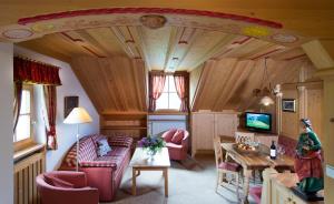ein Wohnzimmer mit einem Sofa und einem TV in der Unterkunft Hotel Ansitz Jakoberhof in St. Ulrich in Gröden
