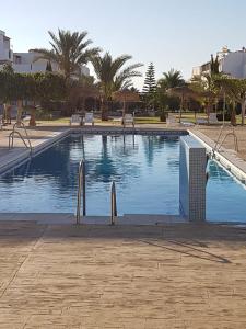 a large swimming pool with palm trees in a resort at CASA BAJA EXTRAORDINARIA EN URBANIZACIÓN NATURISTA! in Las Bombardas