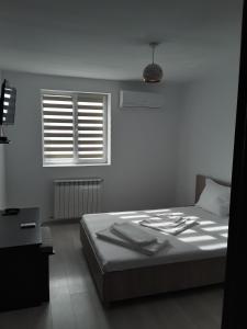 a white bedroom with a bed and a window at Camere de inchiriat Central La Calciu in Mahmudia