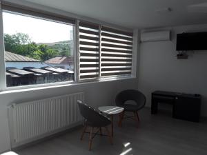 a room with two chairs and a table and two windows at Camere de inchiriat Central La Calciu in Mahmudia
