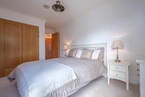 a white bedroom with a large bed and a nightstand at The Point in Exmouth