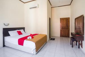 um quarto com uma cama com um urso de peluche sentado sobre ele em RedDoorz near XT Square 2 em Yogyakarta