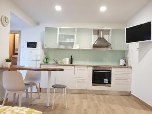 a kitchen with white cabinets and a table and chairs at Apartments Ziher in Zagreb