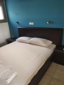 a bed with two white pillows and a blue wall at Mavroforos Hotel in Agios Nikolaos