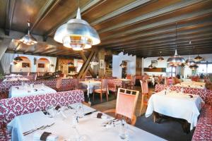 una sala da pranzo con tavoli bianchi e sedie rosse di Hotel Condor a Selva di Val Gardena