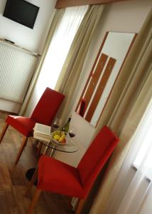 a living room with a table and two red chairs at Hotel Klammwirt in Feldthurns