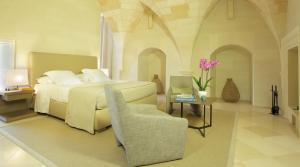 a bedroom with a bed and a chair and a table at La Fiermontina Luxury Home Hotel in Lecce