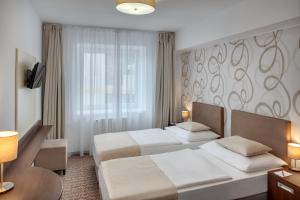 una camera d'albergo con due letti e una finestra di Hotel Atlas a Benešov
