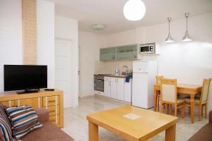 a living room with a kitchen and a table with a television at Apartments4you Dinara in Bat Yam