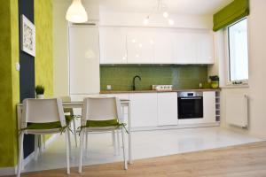 kuchnia z białymi szafkami oraz stołem i krzesłami w obiekcie Natura Apartament w mieście Gdynia