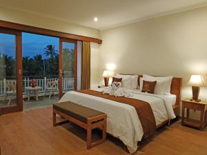 a bedroom with a large bed and a balcony at Paon Desa Ubud in Ubud