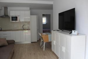 a kitchen and a living room with a television on a cabinet at Apartamentos Angelita Plaza Beach in Málaga