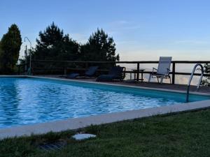 a pool with chairs and a table next to the water at Quinta do Espigueiro in Celorico de Basto